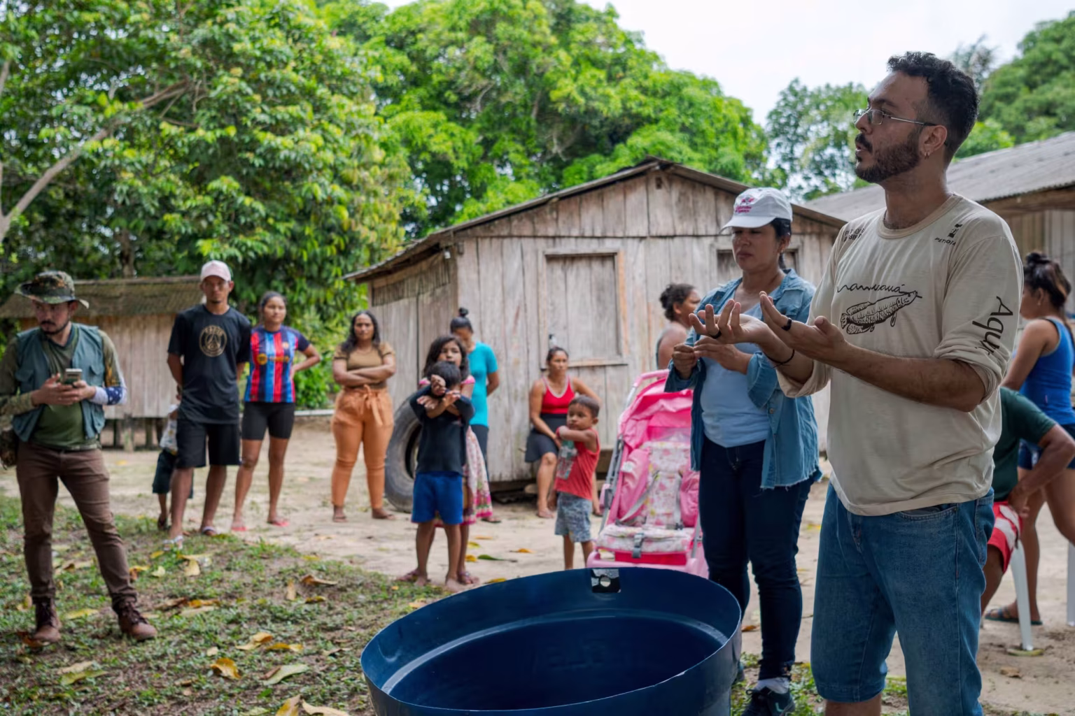 Comunitários reunidos em frente a uma casa de madeira, com uma caixa d’água azul